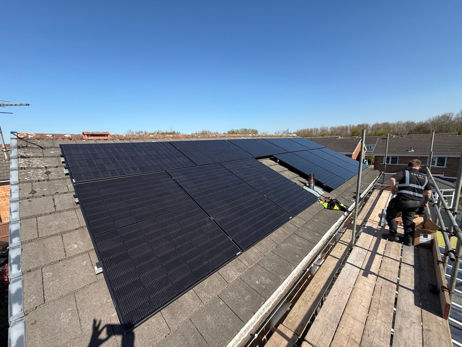 12 all-black solar panels on hook and rail mounting on a tiled roof in Cottam, Preston, with a Smart Group installer on the scaffold