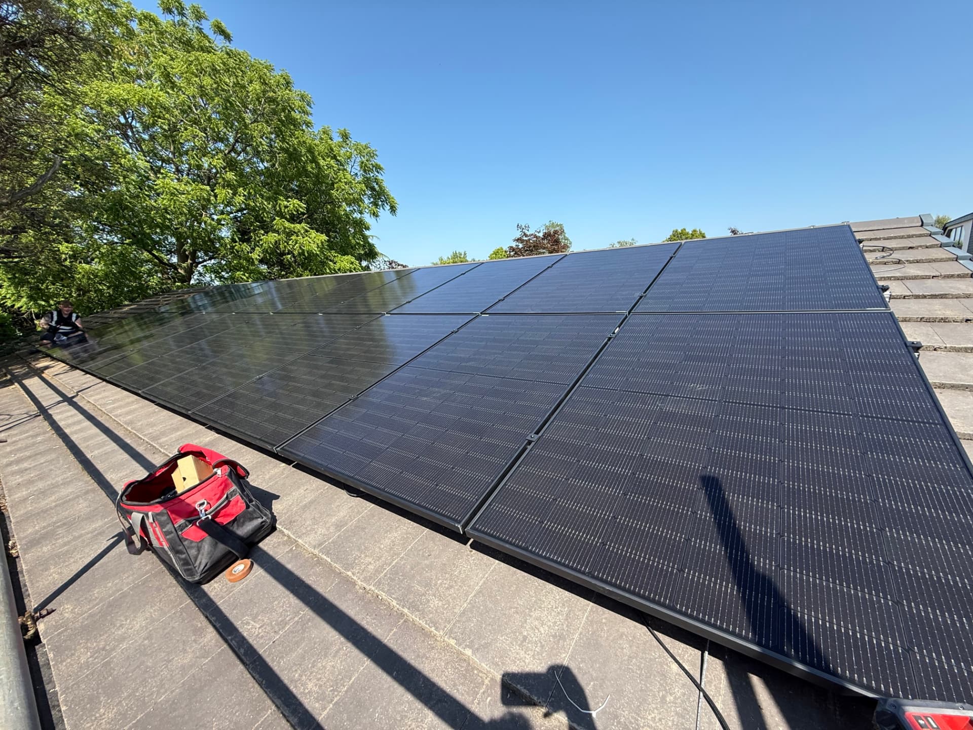 Roof-level view of 20 solar panels on rails on a tiled Croston roof during installation