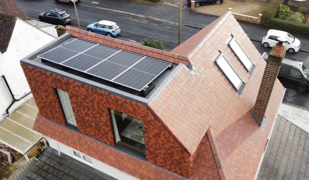 Drone view of 4 solar panels on a flat dormer roof above a tiled extension in Penwortham