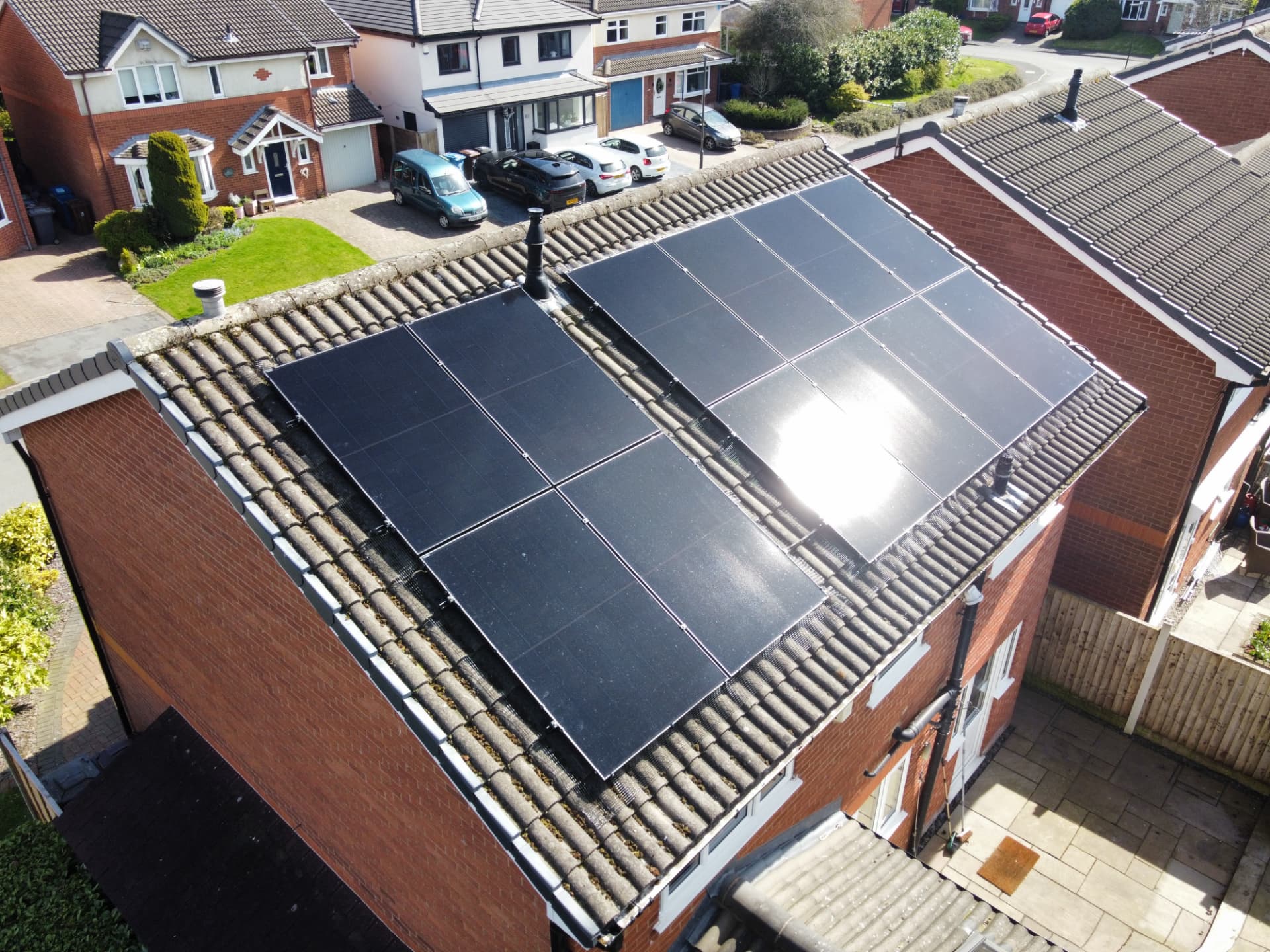 Drone view of 12 solar panels on a tiled roof in Wigan with bird-proofing mesh around the array